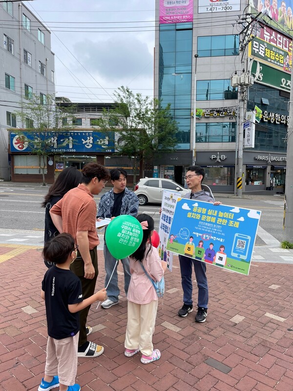 길거리에서 아이들에게 풍선을 나누어주며, 부모에게 조례에 대한 설명을 하고 서명을 받고 있다.